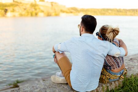 Couple bonding outdoors while gazing at waterの写真素材