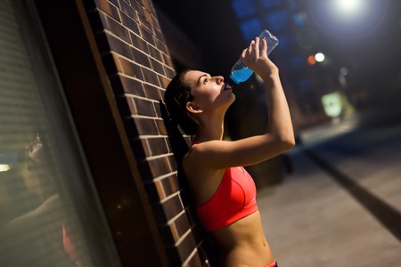 Thirsty sportswoman drinking water after workoutの写真素材