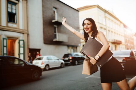 Businesswoman catching a taxi by wavingの写真素材