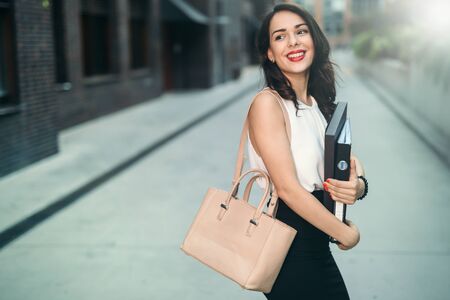 Beautiful businesswoman carrying folders outdoorsの写真素材