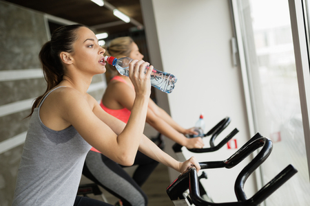 Sporty woman hydrating during workout in gymの写真素材