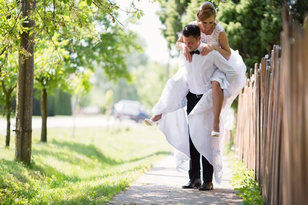 Groom carrying bride piggyback outdoorsの写真素材
