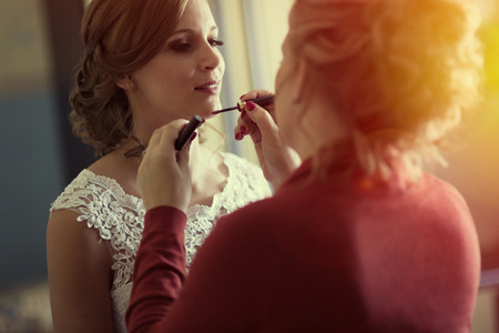 Bride makeup being done by sister at homeの写真素材