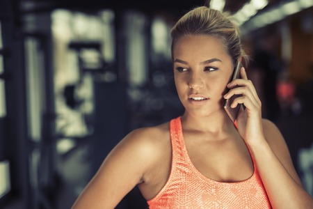 Woman using phone in gymの写真素材