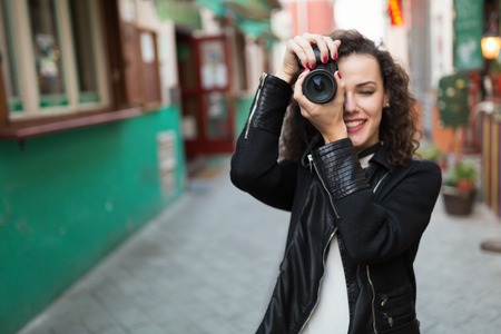 Beautiful woman taking pictures outdoors and smilingの写真素材