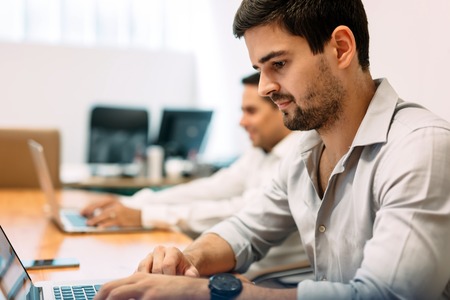 Businesseople working on laptops in office