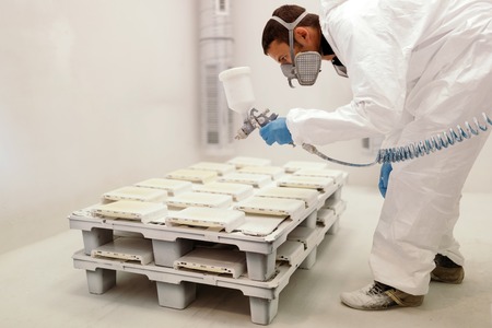 Painter using airbrush to paint wearing protective clothing