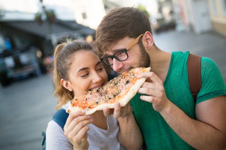 Happy couple eating fast food in city and smilingの写真素材
