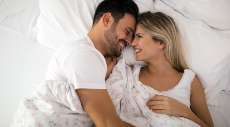 Romantic couple in bed in nightwear smilingの写真素材