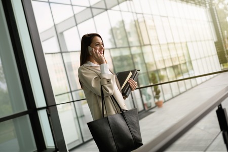 Company CEO busy talking on phone while holding foldersの写真素材