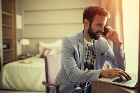 Busy businessman working from home on laptop and phoneの写真素材