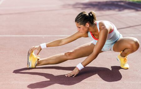 Beautiful young athletic woman stretching in summer before running