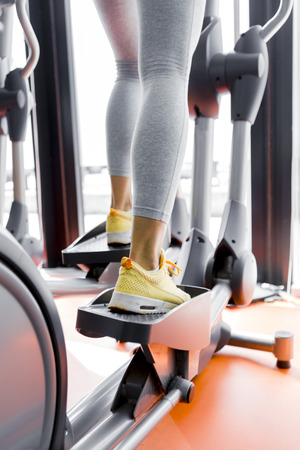 Closeup shot of legs of a female using elliptical trainer in a gymの写真素材