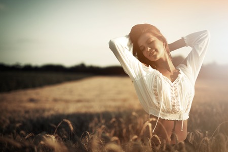 Beautiful carefree woman in fields being happy outdoorsの写真素材