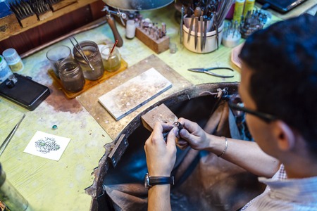 Goldsmith working on his bench, crafting jewelryの写真素材