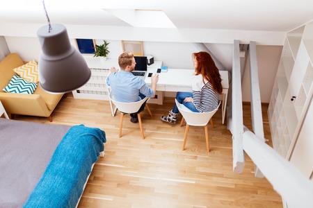Beautiful couple working at home using technologyの写真素材