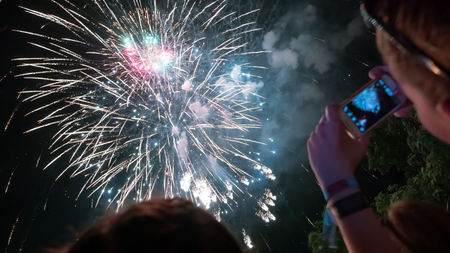 Woman enjoying fireworks celebration and taking photos