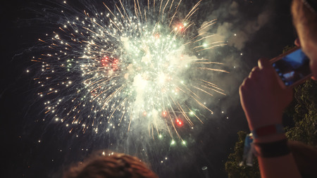 Woman photographing fireworks celebration with phone