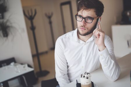 Serious businessman on coffee break using phoneの写真素材