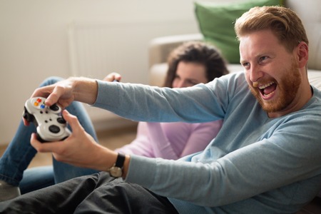 Happy couple playing video games  on console and having funの写真素材