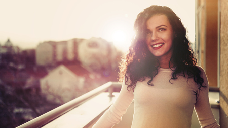 Beautiful woman enjoying sunset on balconyの写真素材