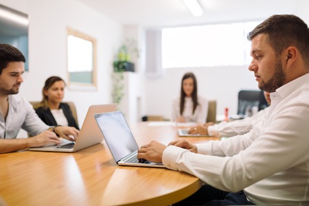 Businesspeople working in office on laptopsの写真素材