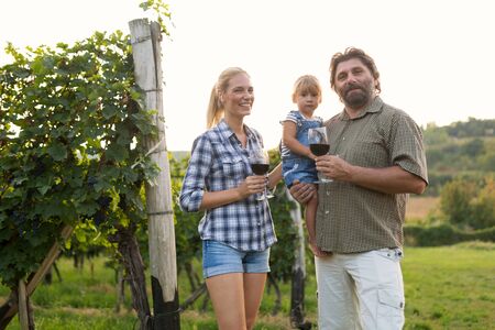 Wine grower family tasting wine in winery vineyardの写真素材