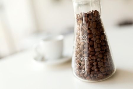 Roasted coffee beans on table with cappuccinoの写真素材