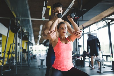 Personal trainer helping woman reach goals in gymの写真素材