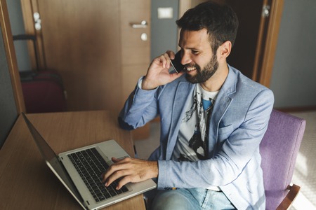 Businessman working on laptop and talking on phone