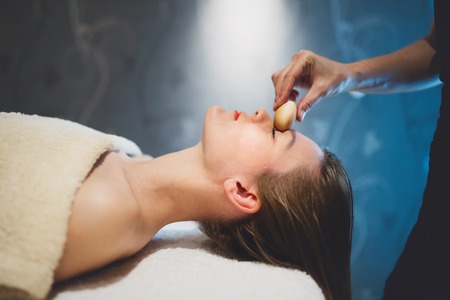 Masseur massaging face with heated wooden objectsの写真素材