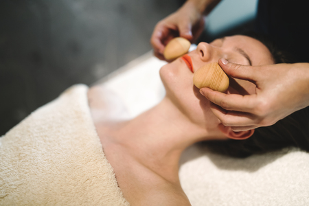 Masseur massaging face with heated wooden objectsの写真素材