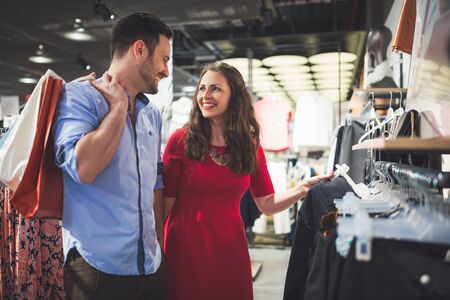 Couple in love shopping in store for clothes carrying bagsの写真素材