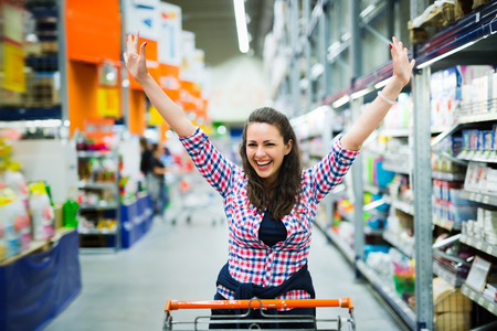 Shopaholic woman enjoying shopping spree in supermarketの写真素材