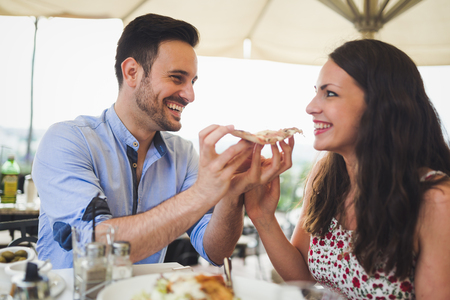 Romantic couple sharing a slice of pizza outdoorの写真素材