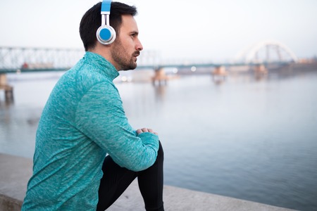 Handsome healthy sportsman exercising while enjoying musicの写真素材