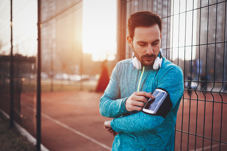 Handsome healthy sportsman exercising while enjoying musicの写真素材