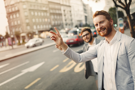 Businessman waving for a taxi in busy cityの写真素材