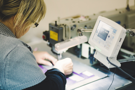 Worker in textile industry sewing on machineの写真素材