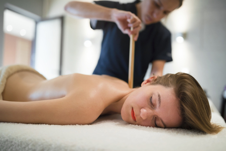 Masseur massaging female on bed while she relaxesの写真素材