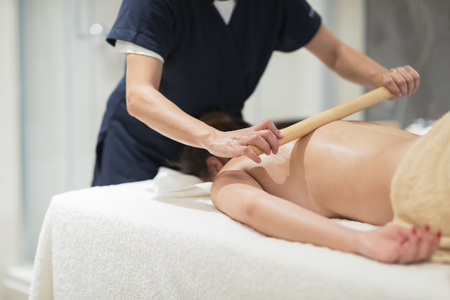 Masseur using massage bamboo sticks during treatmentの写真素材
