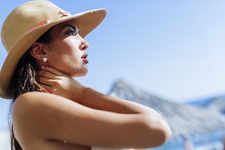 Glamorous woman looking towards the sun while wearing a hatの写真素材