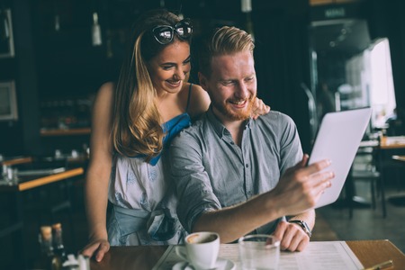 Woman and man flirting in cafe while discussing tablet contentの写真素材