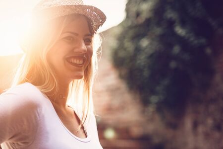 Happy blond female wearing hat outdoor and smilingの写真素材