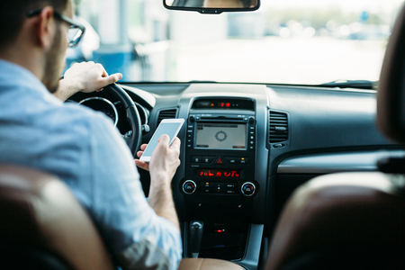 Businessman ignoring safety and texting onmobile phone while drivingの写真素材