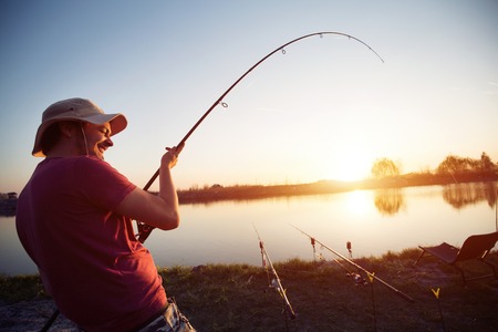 Fishing as recreation and sports displayed by fisherman at lakeの写真素材