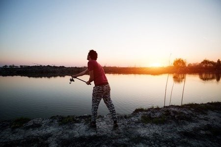 Fishing as recreation and sports displayed by fisherman at lakeの写真素材