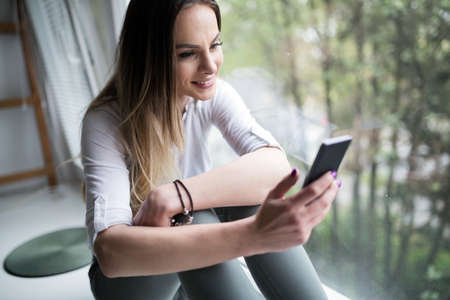 Woman using cell phone at home to connect to social media networ