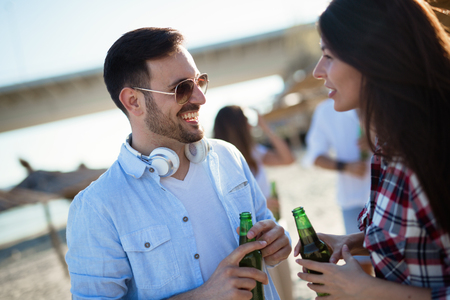 Happy couple having fun and drinking at beachの写真素材