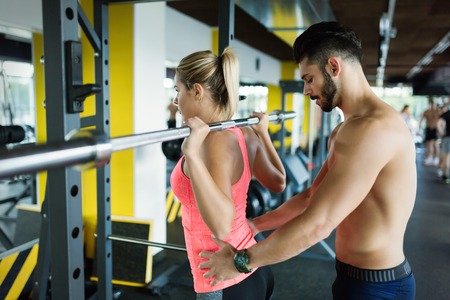 Woman doing squats with her personal trainerの写真素材